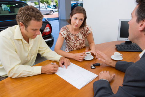 Couple signing lease with car dealer