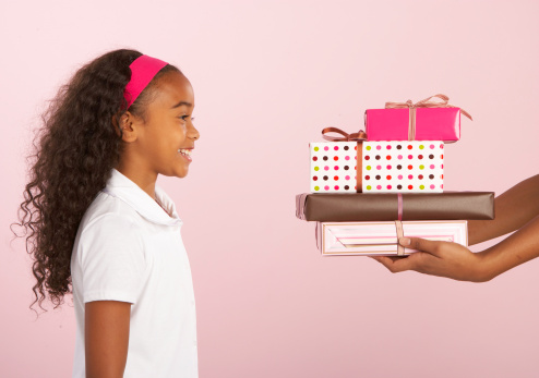 Young woman giving stack of gifts to girl (8-10), side view