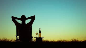 Homem relaxando tomando vinho no por do sol