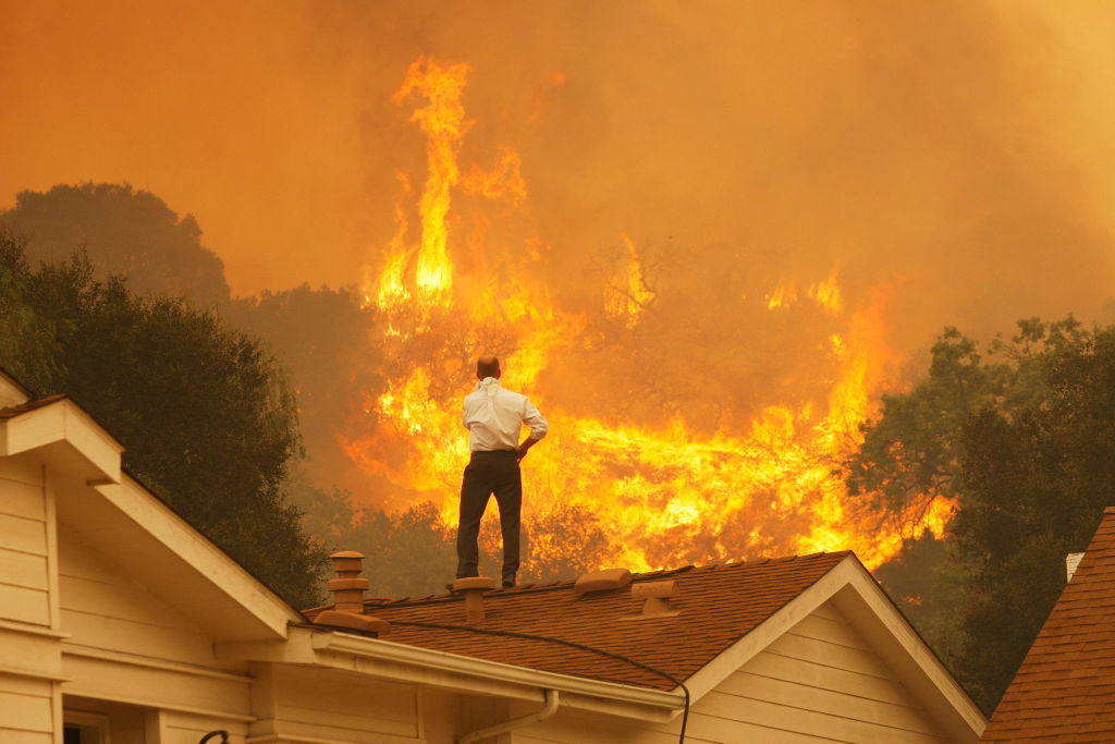 Homem no telhado olha para as chamas se aproximando durante incêndio na Califórnia em 2013 (Foto: David McNew/Getty Images)
