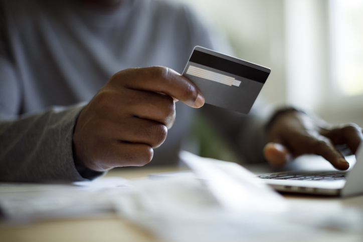 Homem usando um cartão de crédito para pagar contas.