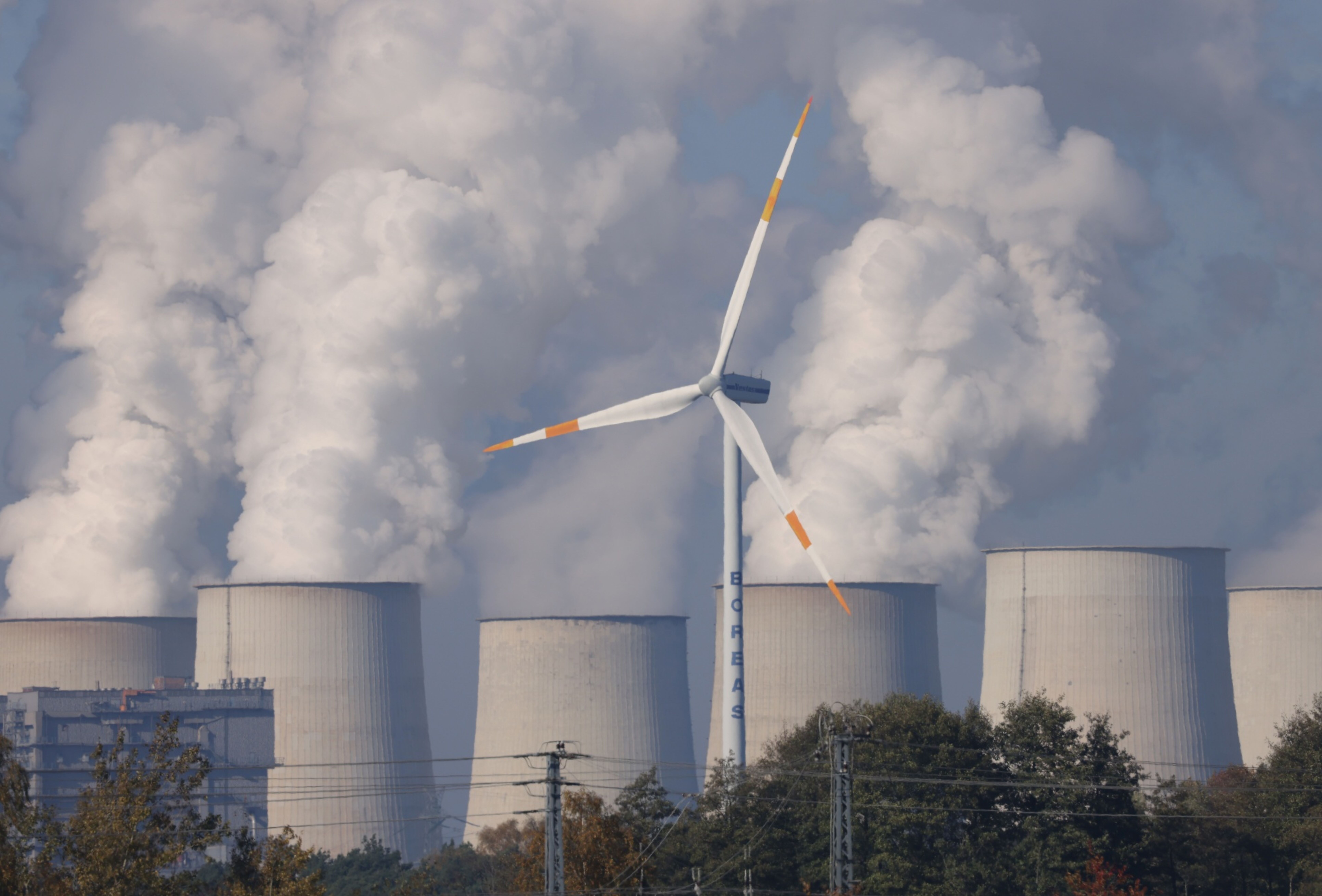 HEINERSBRUECK, GERMANY - OCTOBER 29: A wind turbine spins as steam rises from cooling towers of the Jaenschwalde lignite coal-fired power plant, which is among the biggest single emitters of CO2 in Europe, on October 29, 2021near Heinersbrueck, Germany. While Germany has invested heavily in renewable energy sources, including solar and wind power, over the past decades, it remains dependent on lignite coal for a significant portion of its energy production. And while other countries within the European Union have promised to phase out coal for electricity production within coming years, Germany has made its phase-out pledge for 2038. The COP26 2021 United Nations Climate Change Conference is to begin this coming Sunday in Glasgow. (Photo by Sean Gallup/Getty Images)